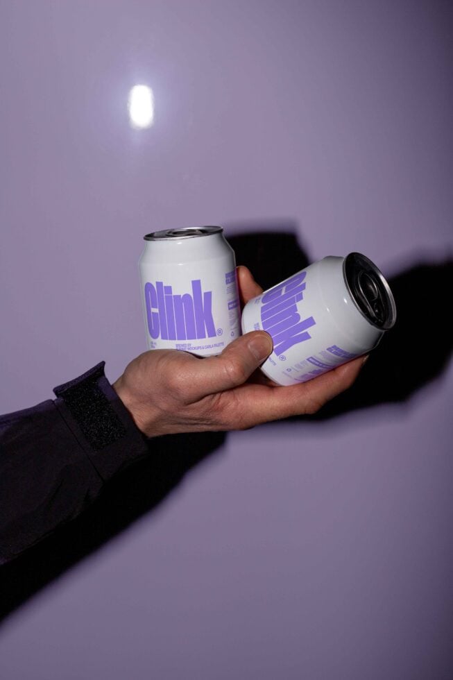 Person holding two white soda cans with Clink branding in purple text. Ideal for product mockup or packaging design. Vibrant modern design asset.