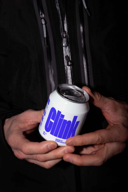 Beer can with bright blue label design held in hands close up shot