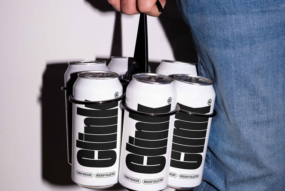 Person in denim holding white six pack carrier with black geometric logo design