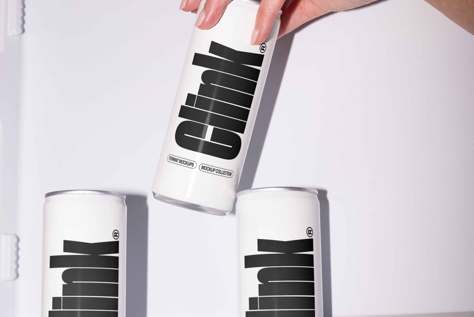 Hand holding white can with black geometric logo while two matching cans sit below