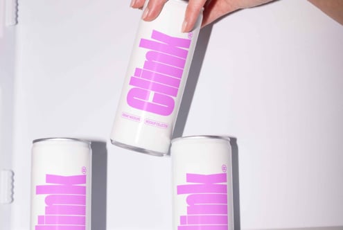 Three white cans with bold pink text spin against a white background. Perfect for beverage branding mockups and product design templates.