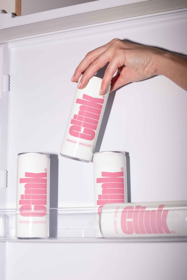 Hand reaching for a sleek drink can mockup in fridge featuring minimalist pink design ideal for designers branding merchandise presentation templates.
