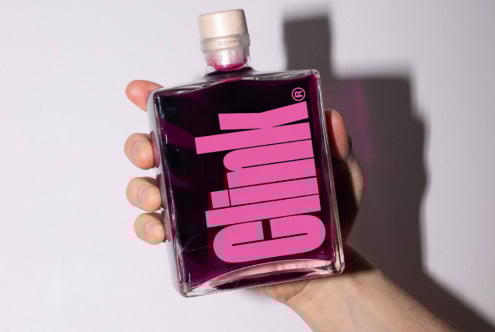 Hand holding a modern square bottle with bold pink typography on a purple background. Perfect for product packaging mockup, design inspiration, or branding.