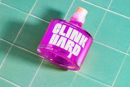 Vibrant purple bottle with bold white text lays on green tiled surface. Ideal for graphic design projects requiring colorful creative elements mockups.