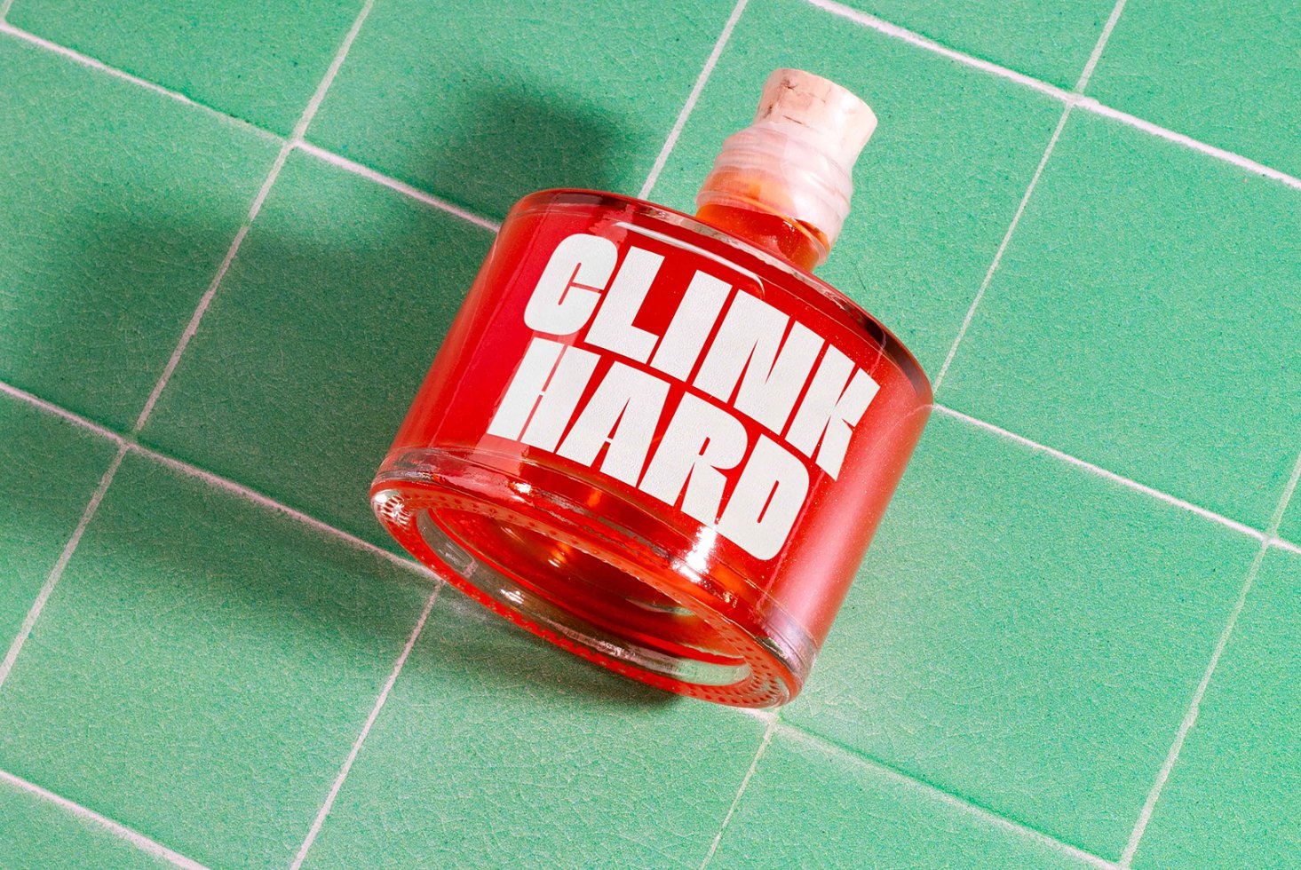 Red bottle labeled Clink Hard on green tiled background. Perfect for graphic mockup projects bold fonts or packaging design digital assets for designers.