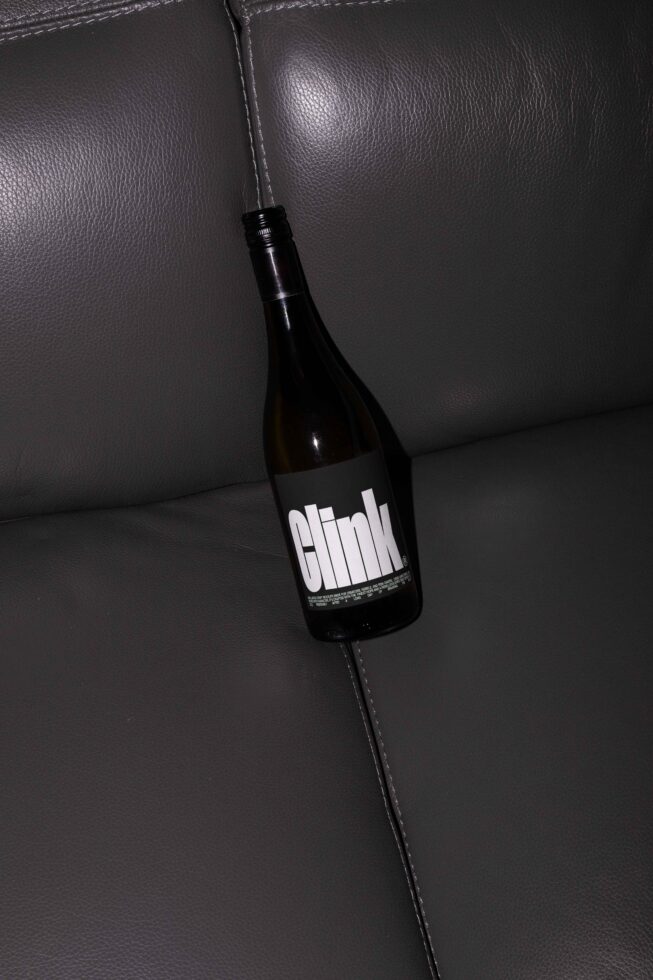 Wine bottle lying on dark leather surface ideal for graphic design mockup showing bold custom label font creative branding asset for designers.