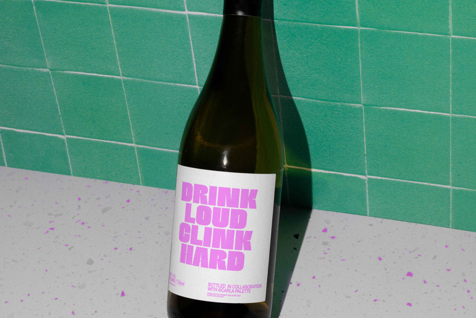 Wine bottle with neon pink label against green tiles, speckled surface