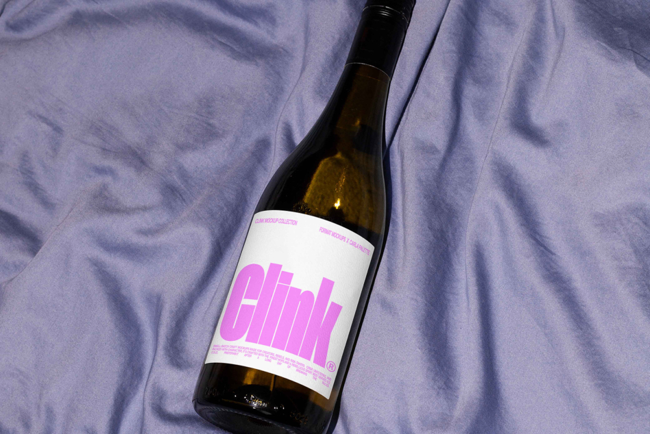 Bottle with bold pink label on purple fabric backdrop, clean minimalist design