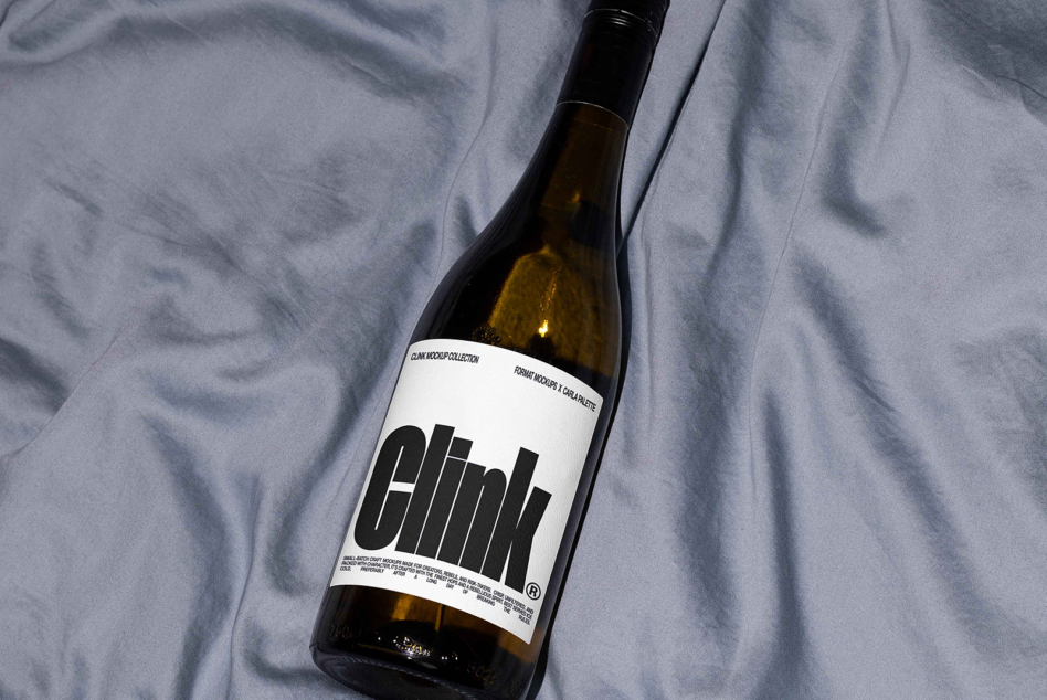 White wine bottle with Clink branding on gray fabric surface, overhead view