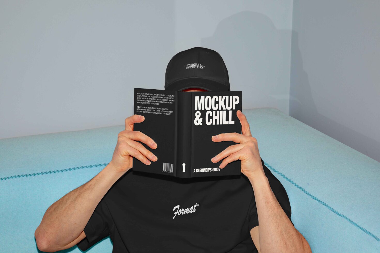 Man holding a book titled Mockup & Chill sitting on a blue sofa. Ideal for mockup designs and branding. Perfect asset for digital designers.