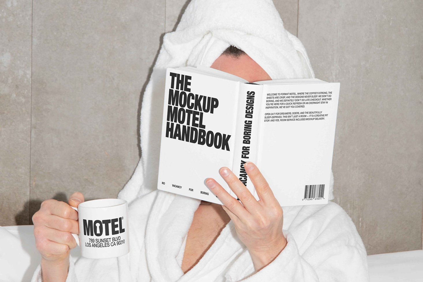 Person in a bathrobe reading The Mockup Motel Handbook with a coffee mug labeled Motel. Ideal for mockup templates, design inspiration, branding.