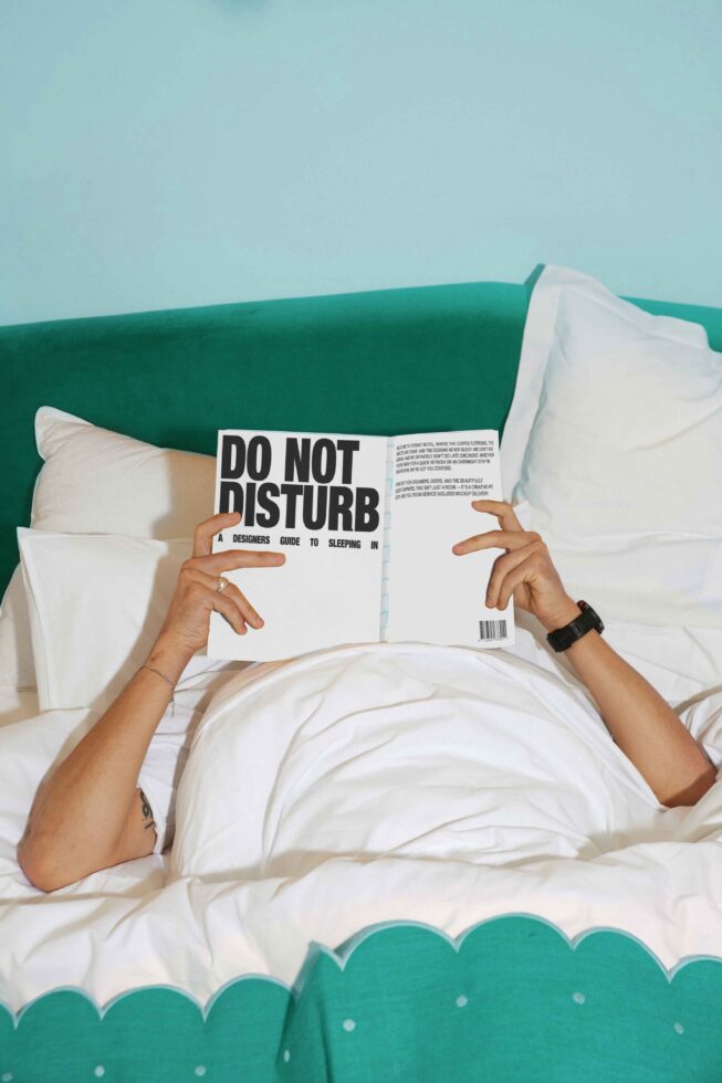 Person reading a book in bed titled Do Not Disturb Designers Guide to Sleeping cozy scene suitable for mockups graphics creative design resources