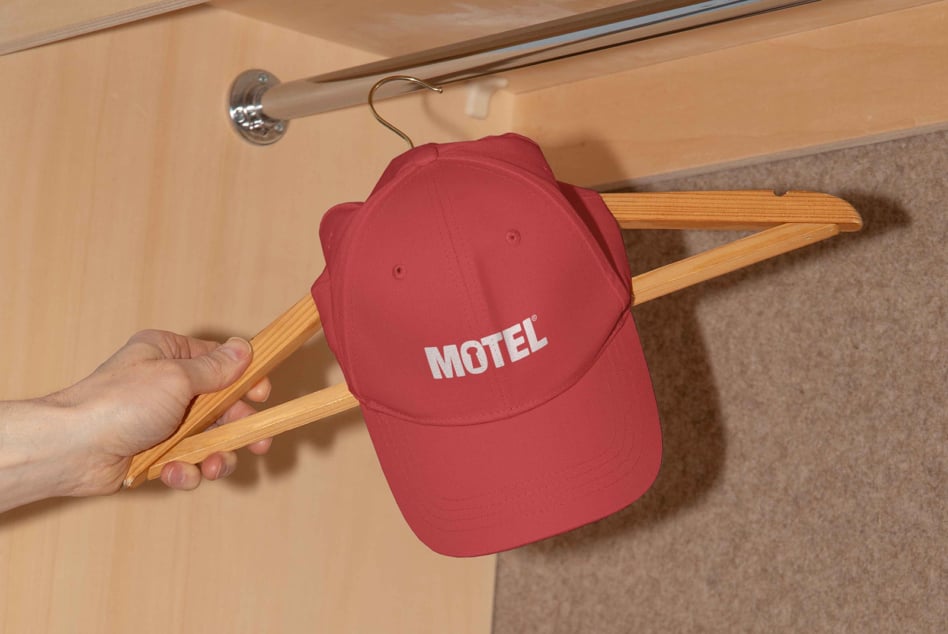 Red cap with MOTEL logo on wooden hanger closet display