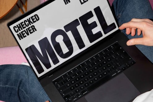 Laptop displaying bold typography design for a motel sign on screen. Designer working on font graphics. Suitable for digital design templates.