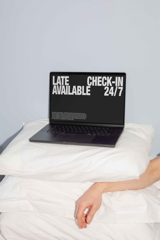 Laptop resting on white pillows with text Late Check-In Available 24 7 minimalist mockup design for digital assets marketplace focused on templates and graphics