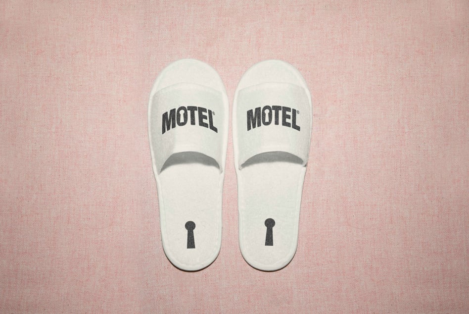 White hotel slippers with MOTEL emblem, keyhole detail on sole