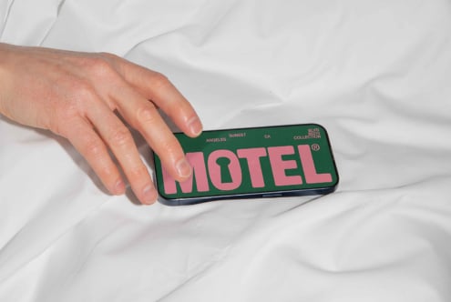 Hand touches phone displaying MOTEL text on green background. Photography mockup for designers stock image digital asset design smartphone screen text.