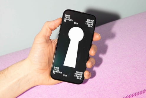 Mockup of a hand holding a smartphone with a keyhole graphic on screen. Text reads Room service fresh mockups delivered to your door. Design resources.