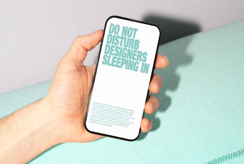 Smartphone mockup displayed in hand featuring text Do Not Disturb Designers Sleeping In ideal for showcasing typography templates and design presentations