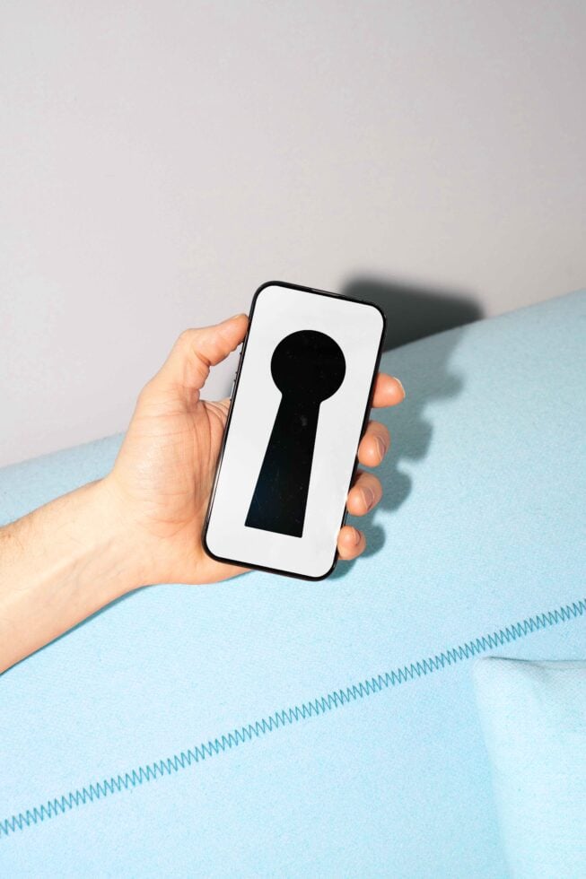 Hand holding smartphone with keyhole graphic on screen. Perfect for security design mockups or app development templates. SEO keywords: mockups templates