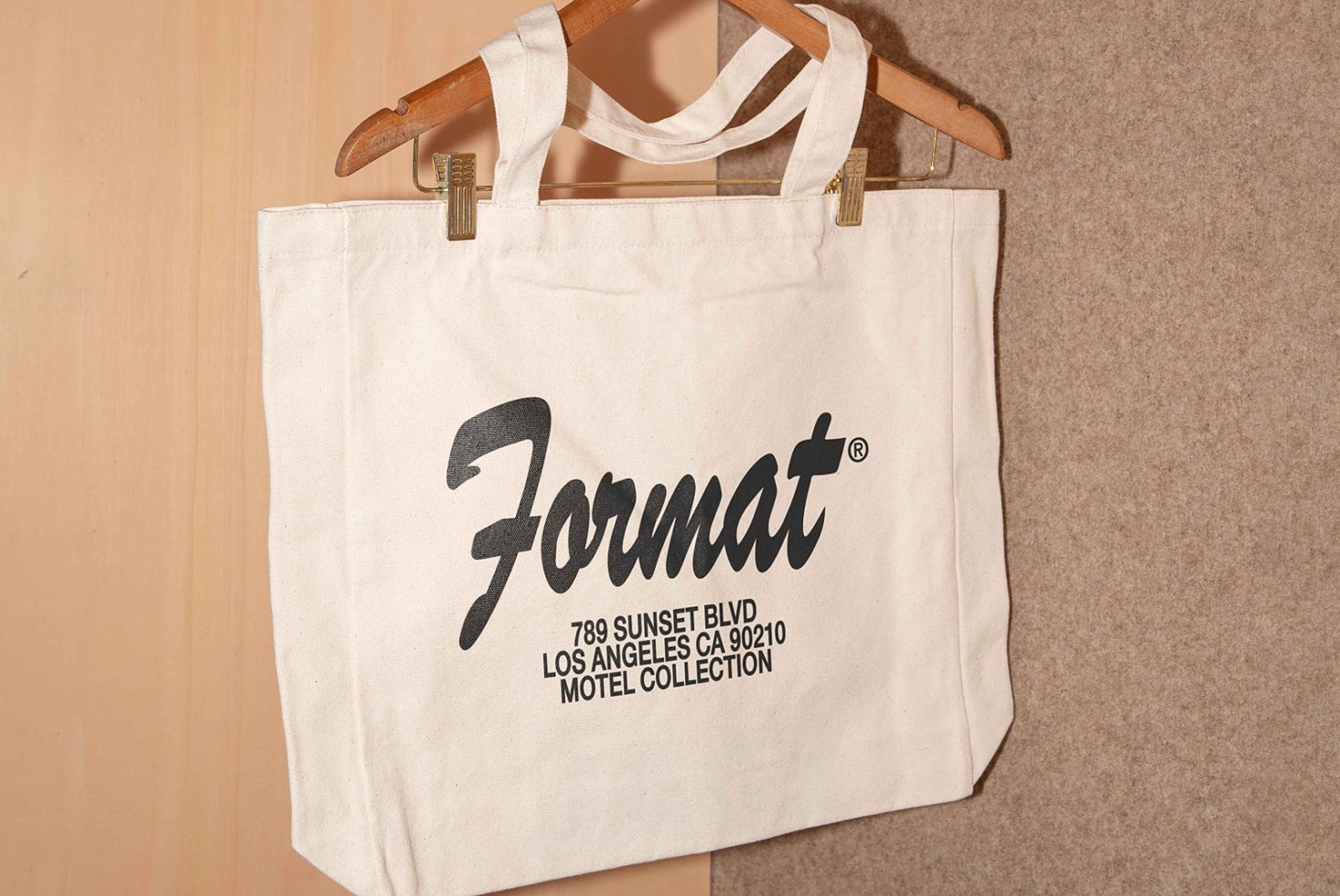 Canvas tote bag with custom typography design featuring Format branding hanging on a wooden hanger perfect for graphic and template design projects.