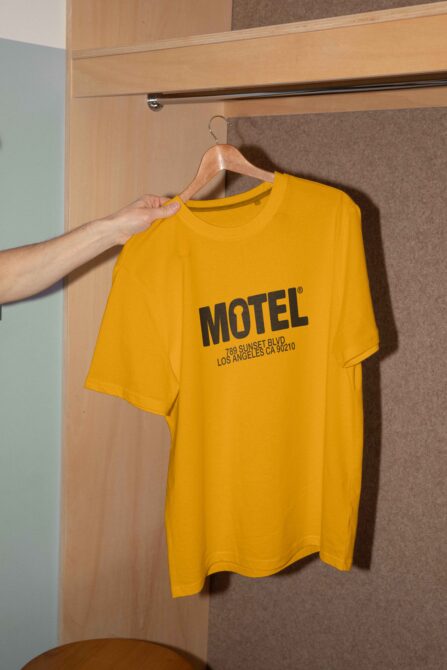 Yellow T-shirt with MOTEL text on hanger in wardrobe mockup design for graphic designers fashion branding apparel showcase digital asset marketing.