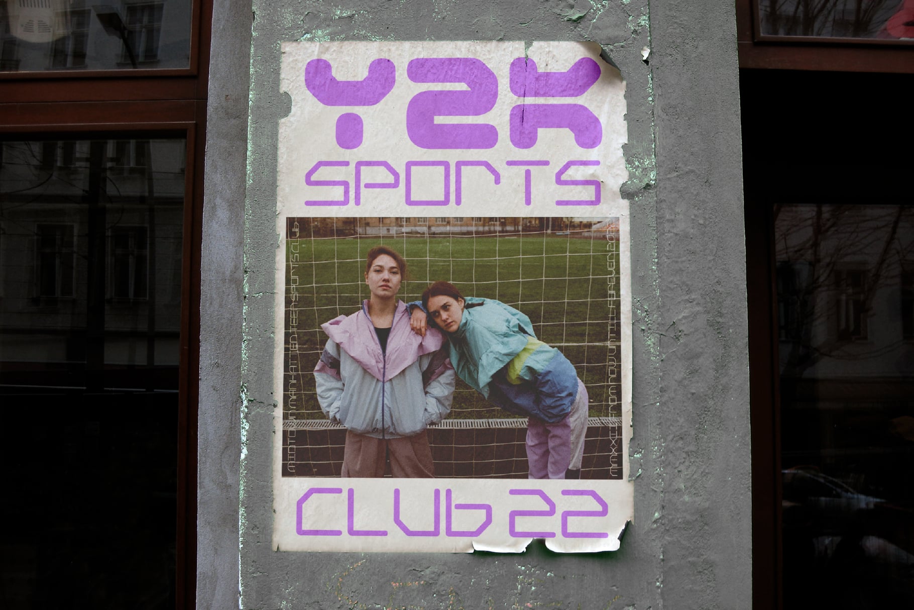 Distressed poster on concrete wall showing purple text, two people posing against chain link
