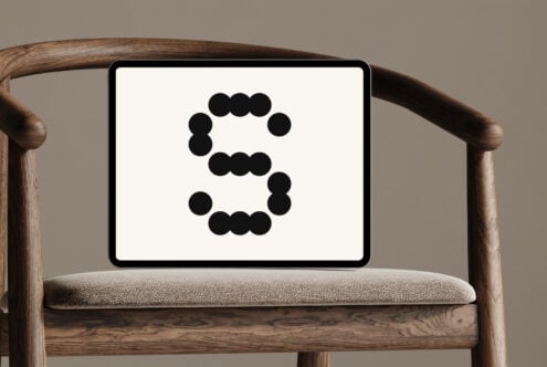 Tablet with minimalist dot-style letter S on chair. Ideal for designers seeking unique typography graphics mockup for digital assets or design projects.