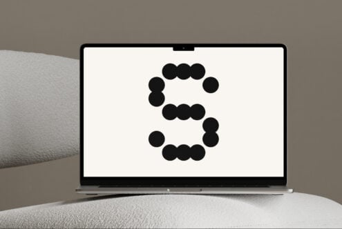 Laptop on a textured surface displaying a bold geometric letter S. Ideal for branding and typography mockups. Modern design for digital assets.