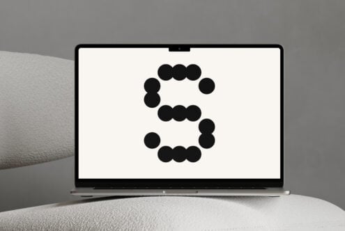 Laptop mockup showing a bold S made of black dots on white screen. Perfect for designers seeking innovative typography presentation or logo concepts.