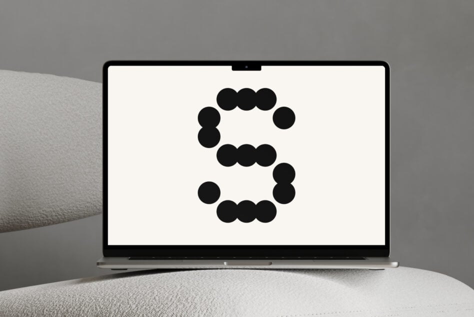 Laptop screen with black dot circle design held by hand overhead