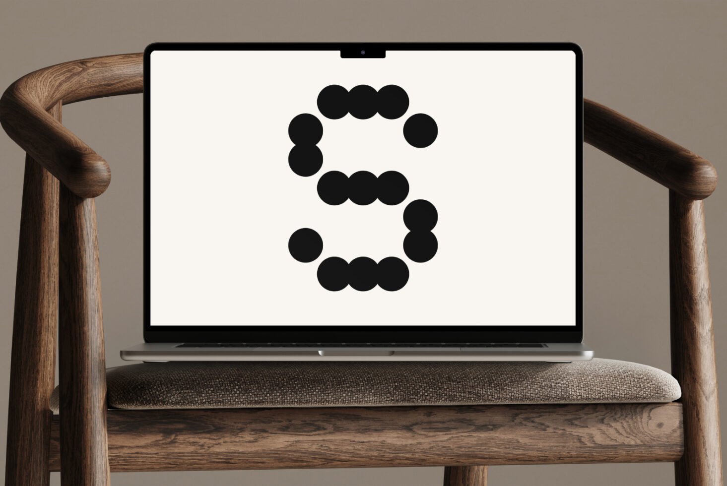 Laptop on wooden chair displaying large stylized letter S made of black dots against neutral background ideal for typography mockup or design assets