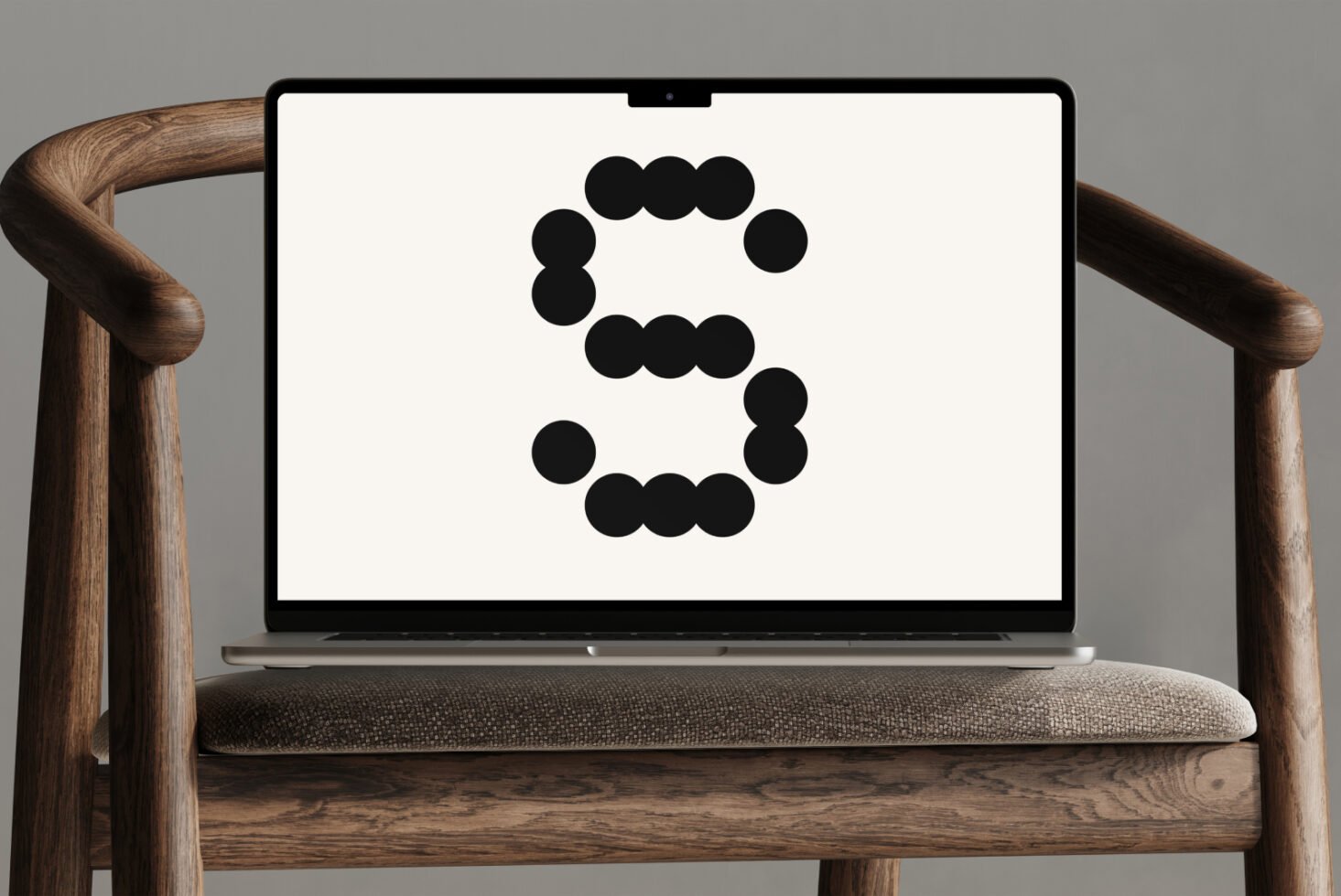Laptop on wooden chair displaying a modern geometric dot font letter S, suitable for designers seeking creative typography, digital mockups, graphic design assets.