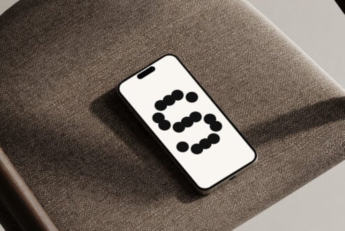Smartphone mockup on textured fabric chair featuring modern dot font display suitable for designers digital assets typography templates SEO graphics.