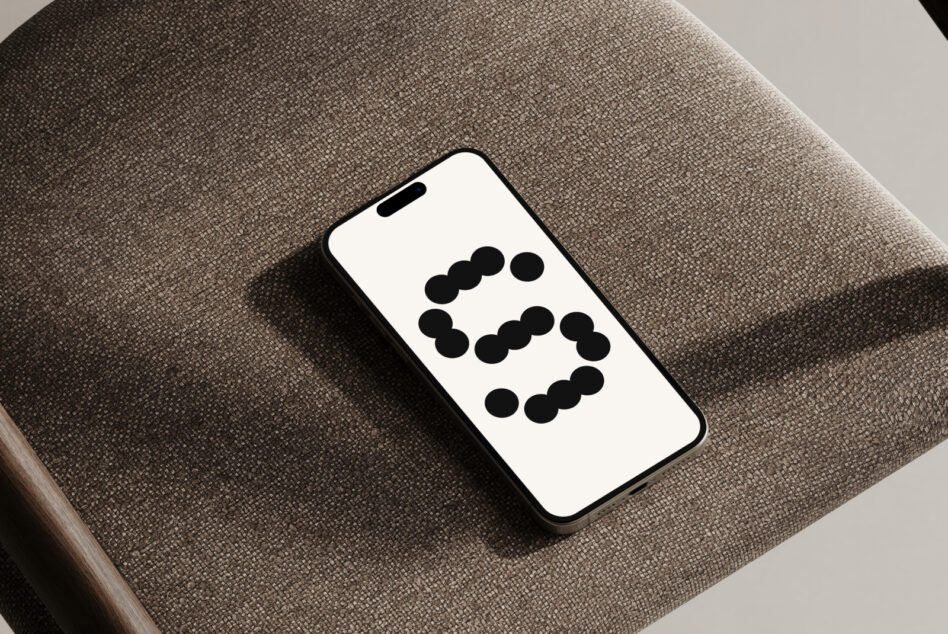 iPhone mockup on taupe chair seat displaying abstract dot arrangement