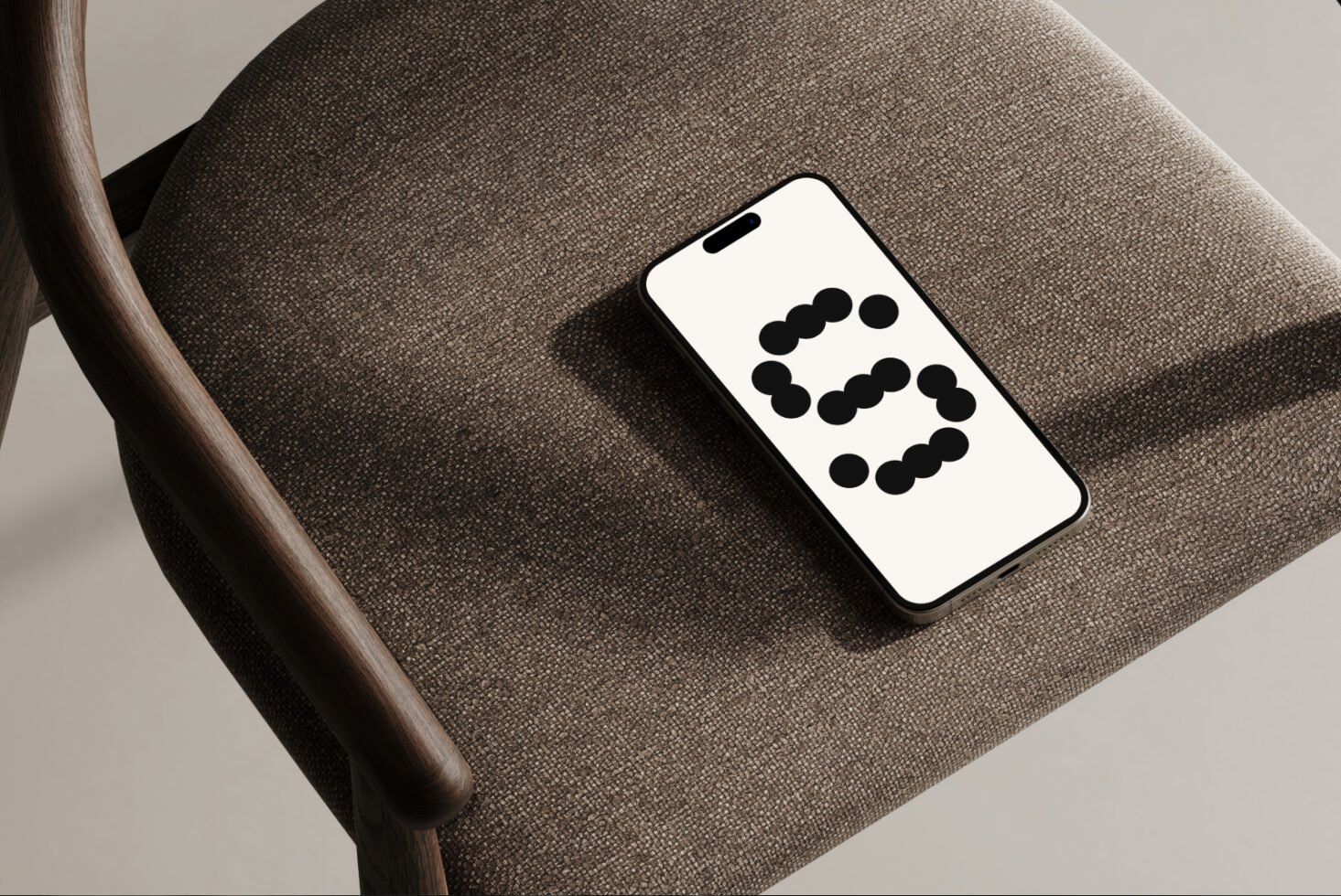 Modern smartphone mockup resting on a textured chair, displaying a geometric pattern, perfect for showcasing app designs and user interface templates.