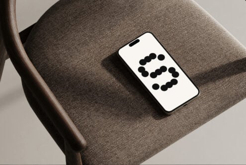 Modern smartphone mockup resting on a textured chair, displaying a geometric pattern, perfect for showcasing app designs and user interface templates.
