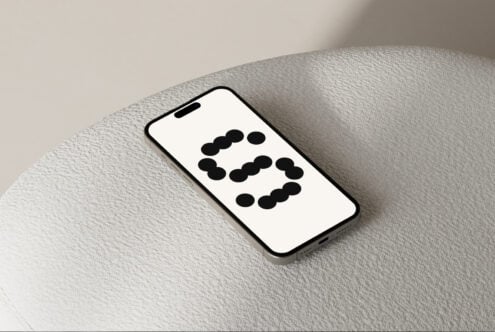 Smartphone mockup on textured surface displaying minimalist black dot pattern. Ideal for designers seeking modern phone screen designs, templates, graphics.