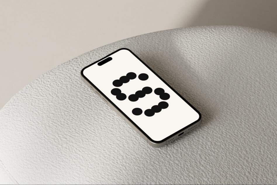 iPhone angled on beige textured cushion with dot pattern mockup visible