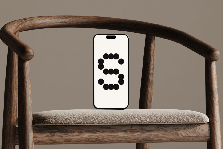 iPhone mockup displaying dot pattern design, propped on mid-century wooden chair
