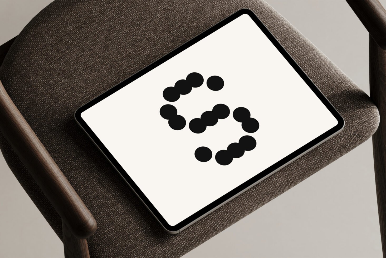 Tablet mockup on chair displaying dotted numeral 5. Perfect for designers needing minimalistic graphic templates. Ideal for showcasing digital assets.