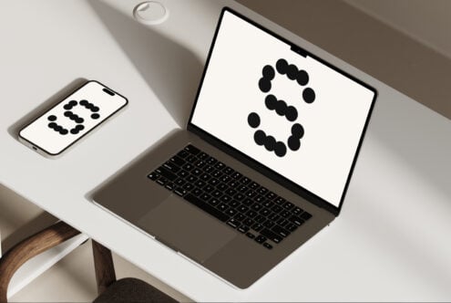 Mockup of a modern laptop and smartphone on a minimalist desk displaying a stylized letter S in a dot font. Perfect asset for graphic design templates.