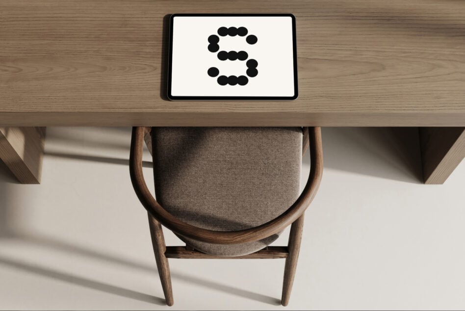 Tablet on wooden desk above mid-century chair displaying dotted number design