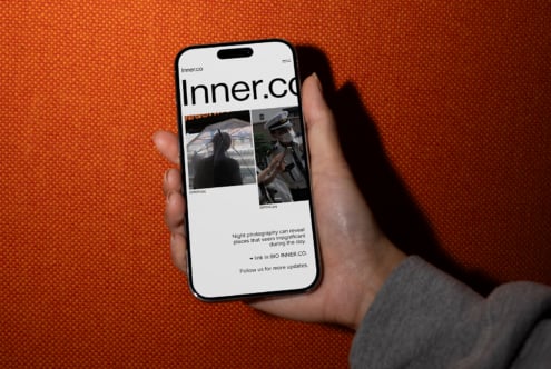 Person holding smartphone with website displayed against orange textile background. Ideal for mockup designs SEO keywords smartphone, website, designer.