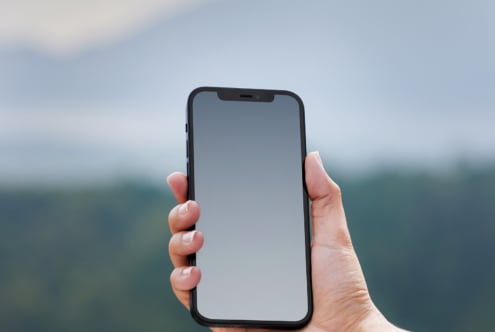 Hand holding smartphone with blank screen outdoors suitable for mobile app mockup digital design template perfect for designers looking for clean layout