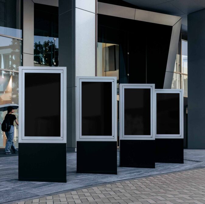 Four outdoor digital billboards with white frames descending in size, all displaying blank black screens
