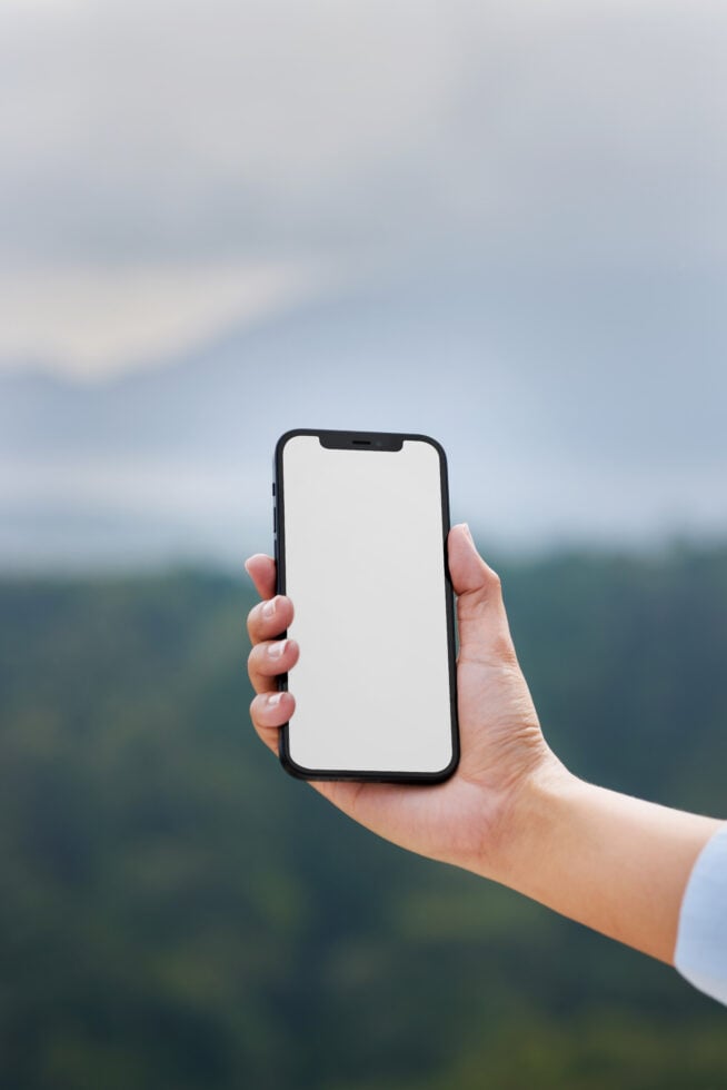 Smartphone mockup held by a hand against a blurred natural background suitable for mobile app display UI showcase digital assets for designers.