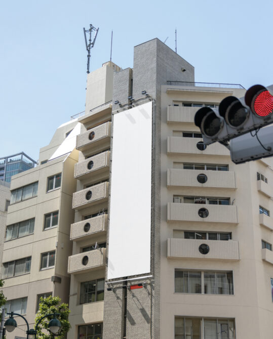 Urban street view with blank billboard between apartment buildings near traffic light