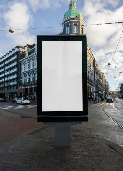 Tall black vertical billboard on urban street corner with historic buildings