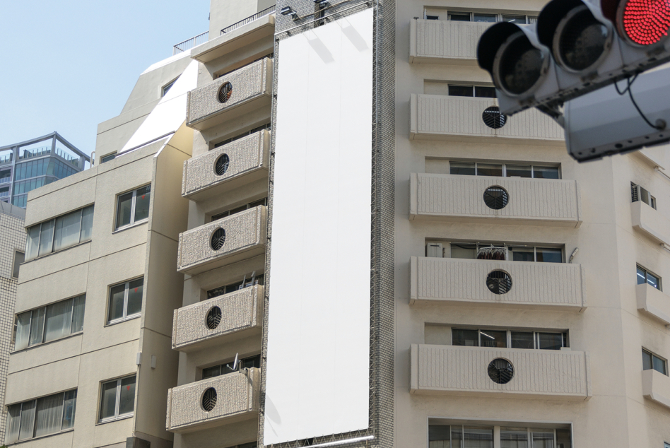 Street level view of empty billboard on building facade with red traffic signal